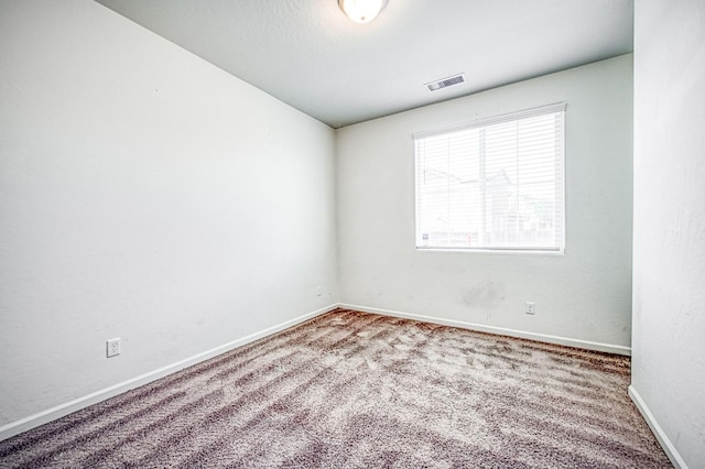 carpeted spare room featuring visible vents and baseboards