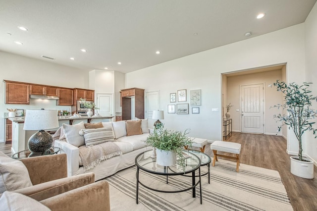 living room featuring baseboards, light wood-type flooring, visible vents, and recessed lighting