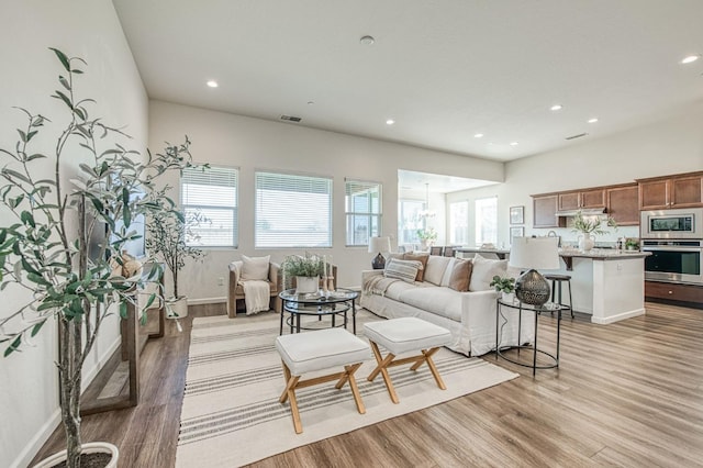 living area featuring visible vents, light wood-style flooring, a wealth of natural light, and recessed lighting