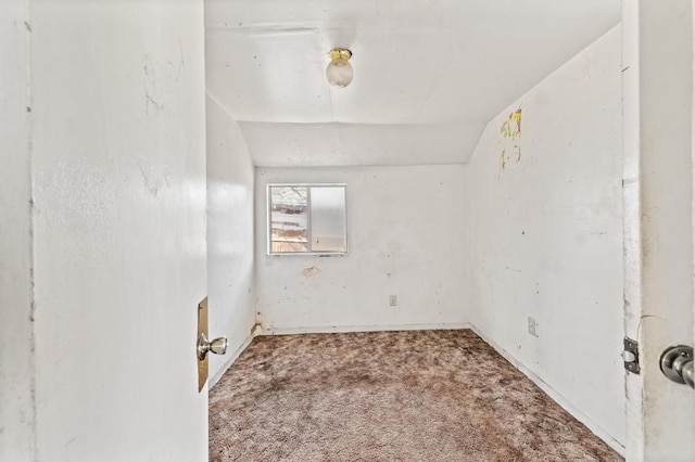 carpeted spare room featuring vaulted ceiling