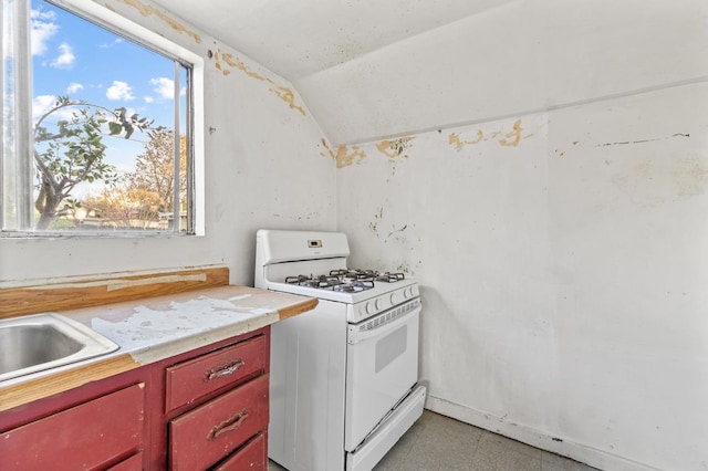 kitchen with lofted ceiling, white gas stove, red cabinetry, and light countertops