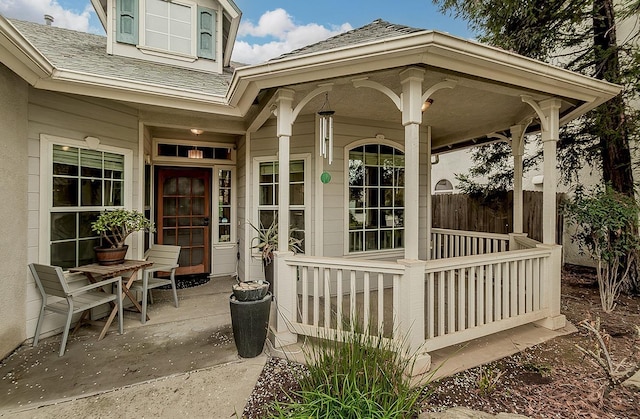 doorway to property with a shingled roof and fence