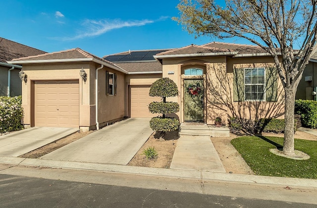 ranch-style house with a garage, concrete driveway, stucco siding, and solar panels