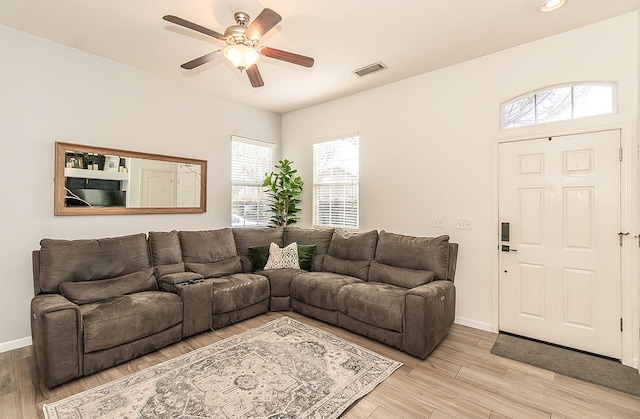 living room with visible vents, ceiling fan, light wood-style flooring, and baseboards