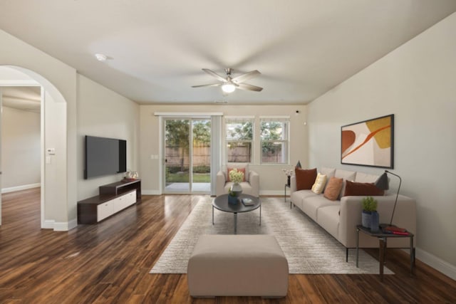 living area with arched walkways, dark wood-style flooring, ceiling fan, and baseboards