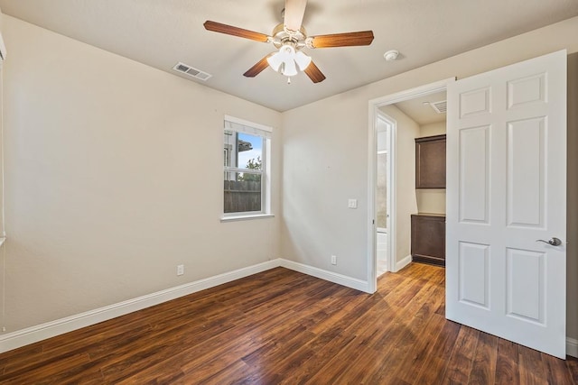 empty room with ceiling fan, dark wood finished floors, visible vents, and baseboards