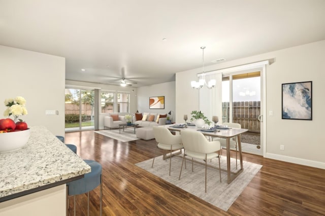 dining space with visible vents, baseboards, dark wood finished floors, and ceiling fan with notable chandelier