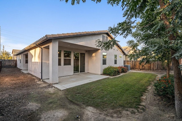 rear view of house featuring a fenced backyard, a yard, central air condition unit, a patio area, and stucco siding