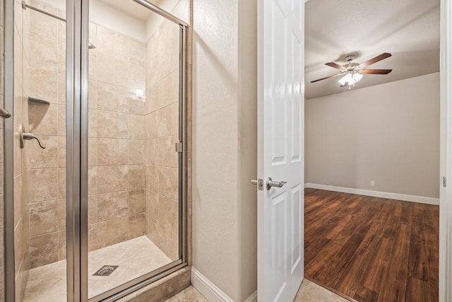 bathroom with baseboards, wood finished floors, and a shower stall