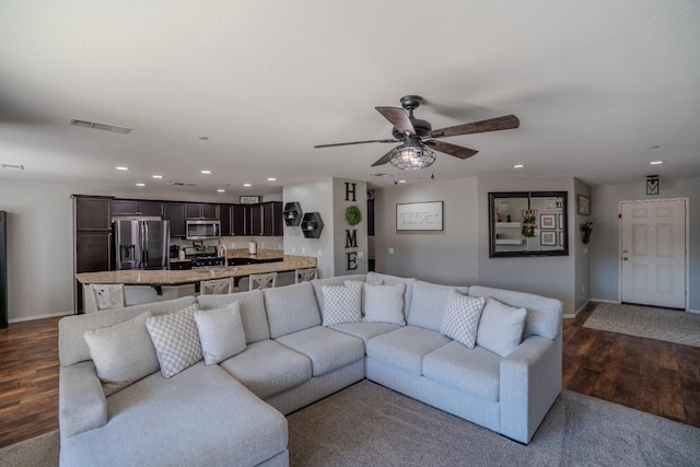 living room with baseboards, visible vents, ceiling fan, dark wood-style flooring, and recessed lighting