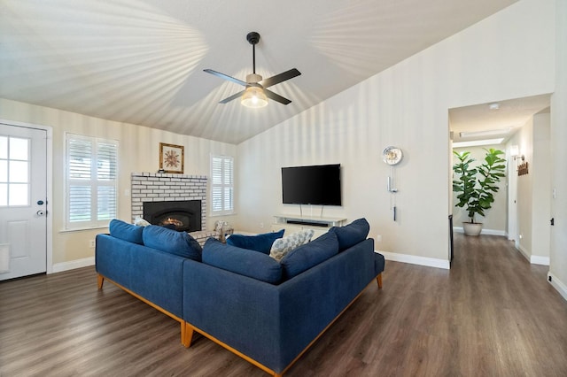 living area with a wealth of natural light, dark wood-style flooring, vaulted ceiling, and a brick fireplace