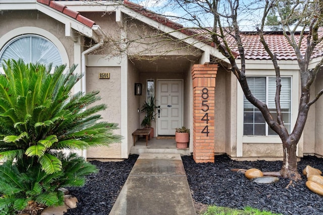 property entrance featuring a tile roof and stucco siding