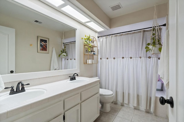 bathroom featuring toilet, a sink, visible vents, and tile patterned floors