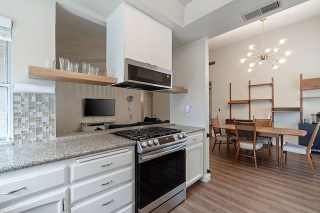 kitchen featuring visible vents, white cabinets, stainless steel appliances, light wood-style floors, and a notable chandelier