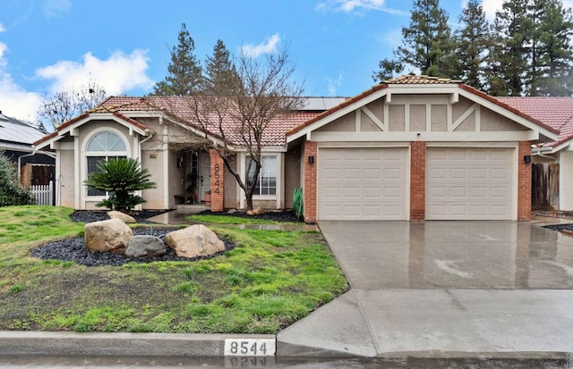 view of front of home with stucco siding, solar panels, a garage, driveway, and a front lawn