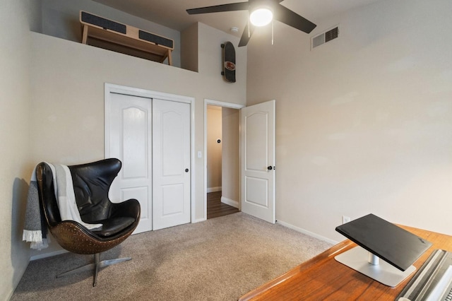 carpeted office space with ceiling fan, a towering ceiling, visible vents, and baseboards