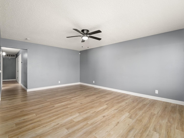 spare room with light wood-type flooring, a textured ceiling, baseboards, and a ceiling fan