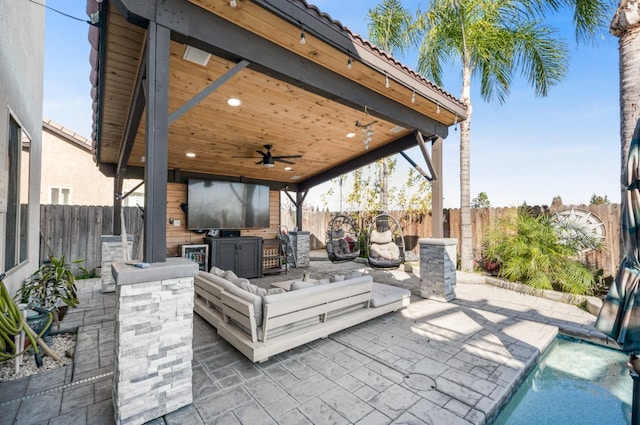 view of patio with an outdoor kitchen, a fenced backyard, and a ceiling fan