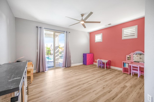 recreation room with light wood-type flooring, visible vents, ceiling fan, and baseboards