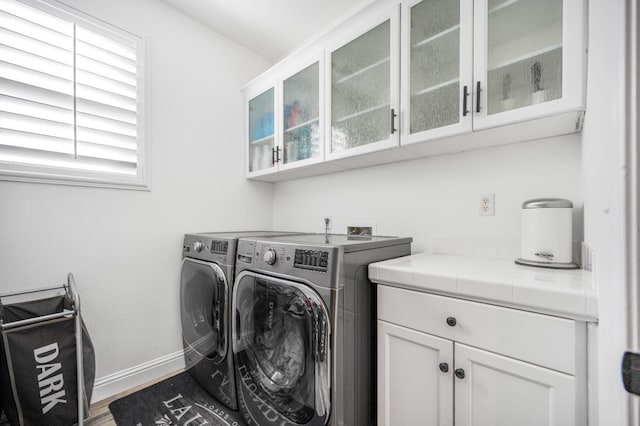 washroom with baseboards, wood finished floors, cabinet space, and washer and dryer