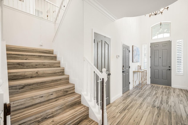 entryway with a high ceiling, light wood finished floors, and stairs