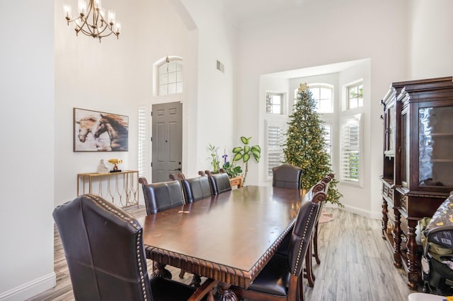 dining area with visible vents, arched walkways, baseboards, light wood-style flooring, and a high ceiling