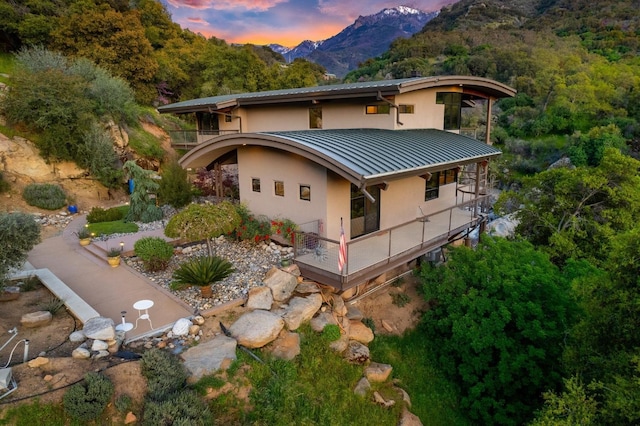 rear view of house featuring a standing seam roof, a mountain view, metal roof, and stucco siding