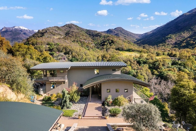 view of front facade featuring a balcony, a mountain view, metal roof, and stucco siding