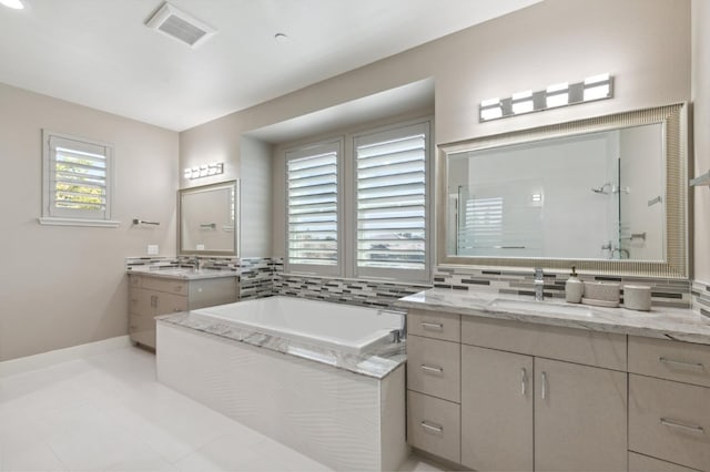 bathroom with a garden tub, two vanities, visible vents, a sink, and walk in shower