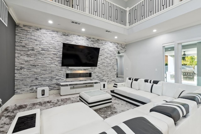 living area with a towering ceiling, visible vents, crown molding, and recessed lighting