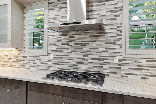 kitchen featuring stainless steel gas cooktop, backsplash, ventilation hood, and dark brown cabinets