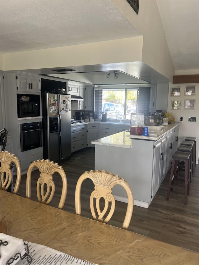 kitchen featuring a peninsula, dark wood-style floors, appliances with stainless steel finishes, and light countertops