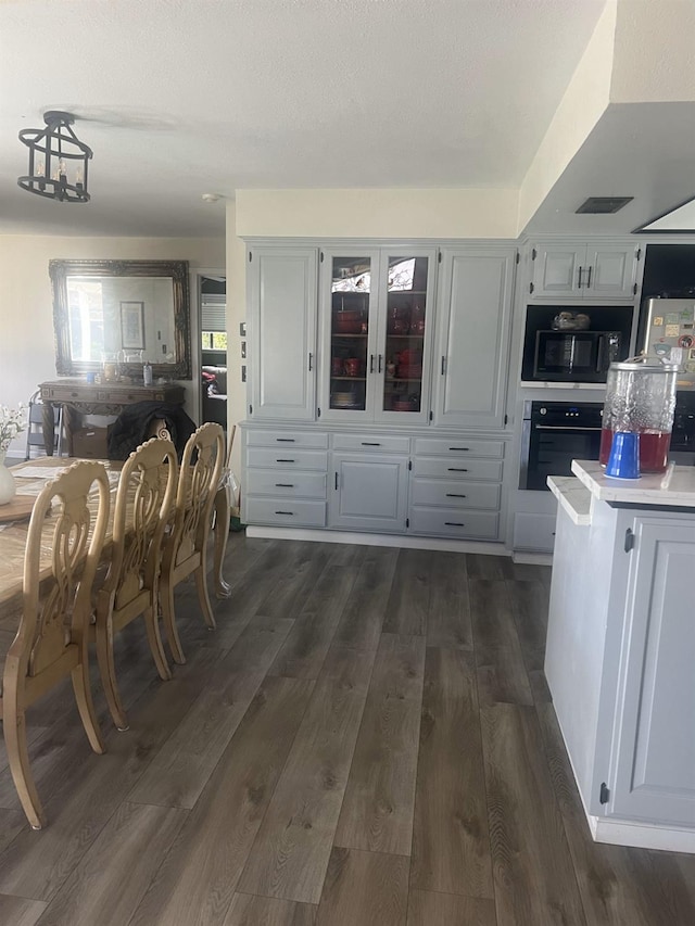 15245 El Mar Ln, Kerman, CA 93630 - kitchen with black microwave, oven, white cabinetry, light countertops, and dark wood-style floors