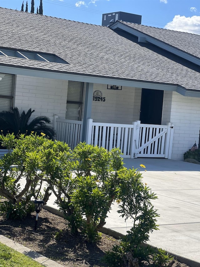 view of side of property featuring a shingled roof, central AC, and a porch