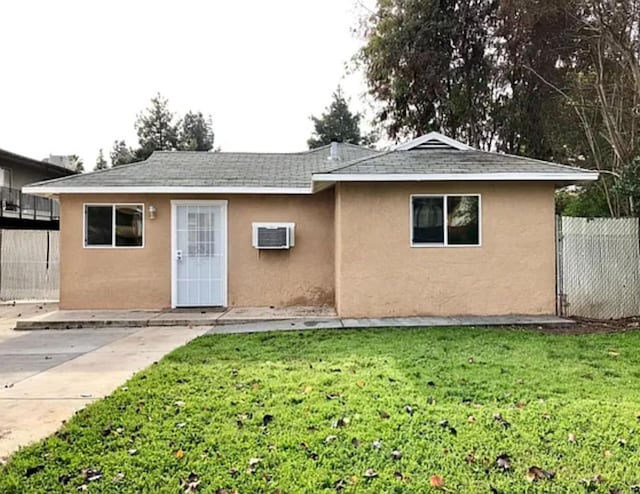 view of front of home with a shingled roof, fence, a patio area, a front lawn, and stucco siding