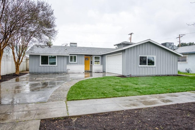 ranch-style house with a garage, fence, driveway, a front lawn, and board and batten siding