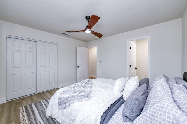 bedroom featuring baseboards, visible vents, a ceiling fan, wood finished floors, and a closet