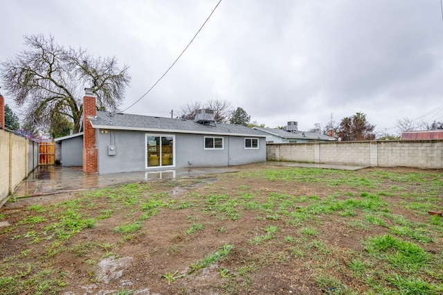 back of house with a patio area, a fenced backyard, central AC unit, and stucco siding