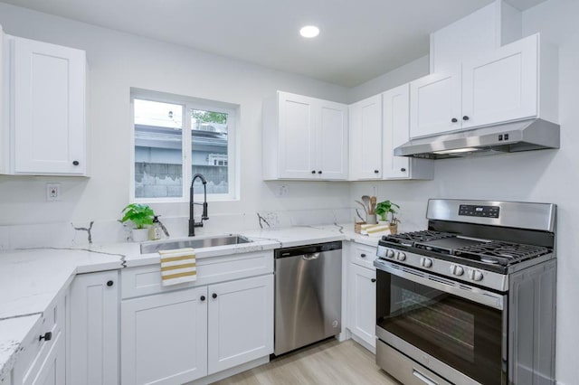 kitchen with appliances with stainless steel finishes, white cabinetry, a sink, and under cabinet range hood