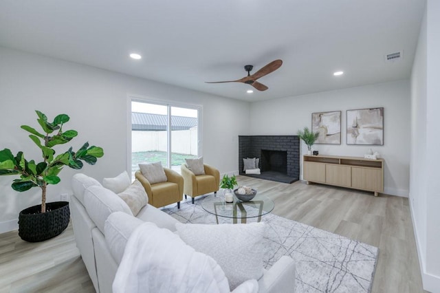 living area featuring recessed lighting, baseboards, a fireplace, and light wood finished floors