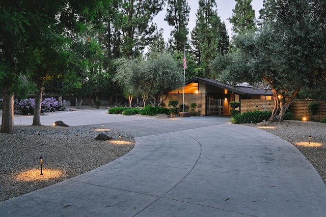 view of front of home featuring roof mounted solar panels, fence, curved driveway, and brick siding