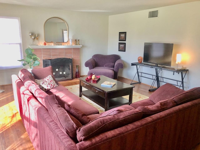 living room with visible vents, a fireplace, and wood finished floors