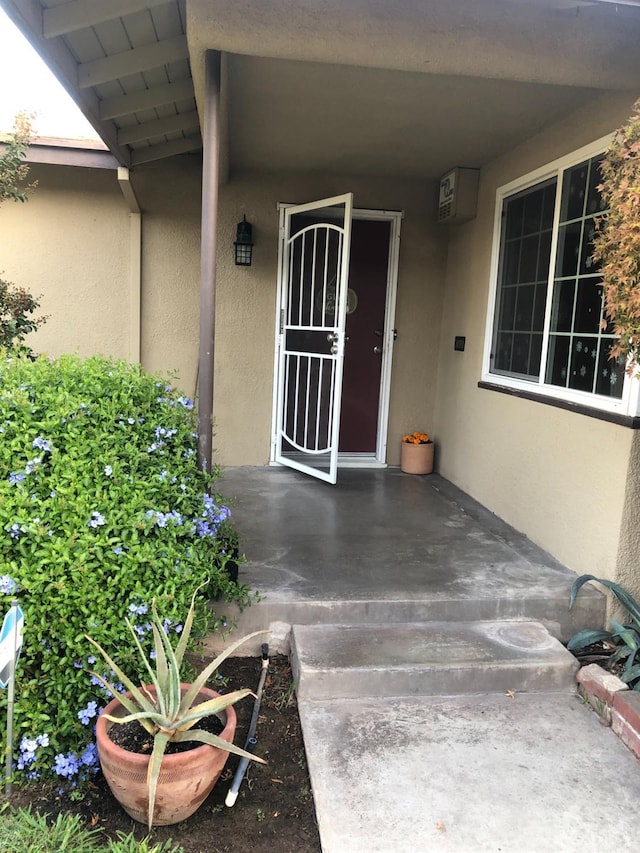 doorway to property with stucco siding and a wall mounted AC