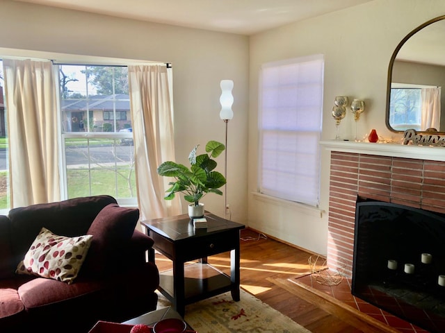 living room featuring a brick fireplace and wood finished floors