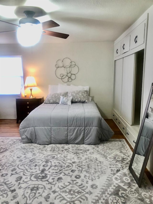 bedroom with a closet, wood finished floors, and a ceiling fan