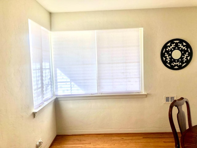 unfurnished dining area featuring visible vents, wood finished floors, and a textured wall