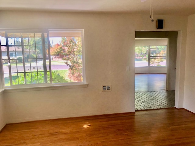 unfurnished room featuring visible vents, baseboards, and wood finished floors