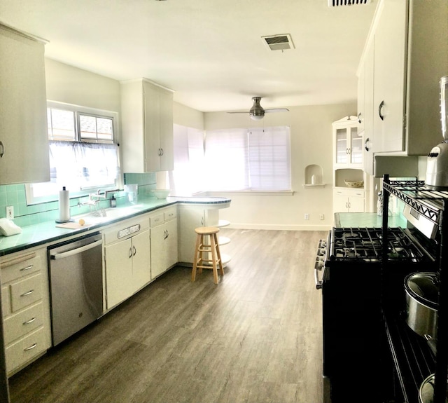 kitchen featuring dark wood-style floors, decorative backsplash, appliances with stainless steel finishes, and white cabinetry