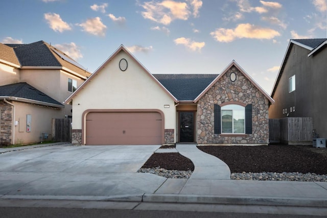 view of front facade with a garage, fence, concrete driveway, and stucco siding