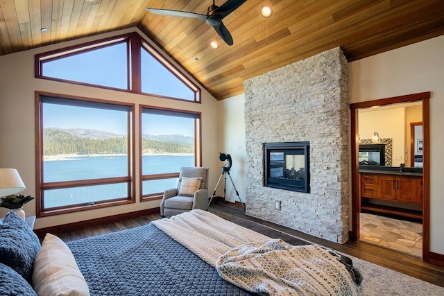 bedroom featuring wood ceiling, wood finished floors, a water view, a stone fireplace, and a sink